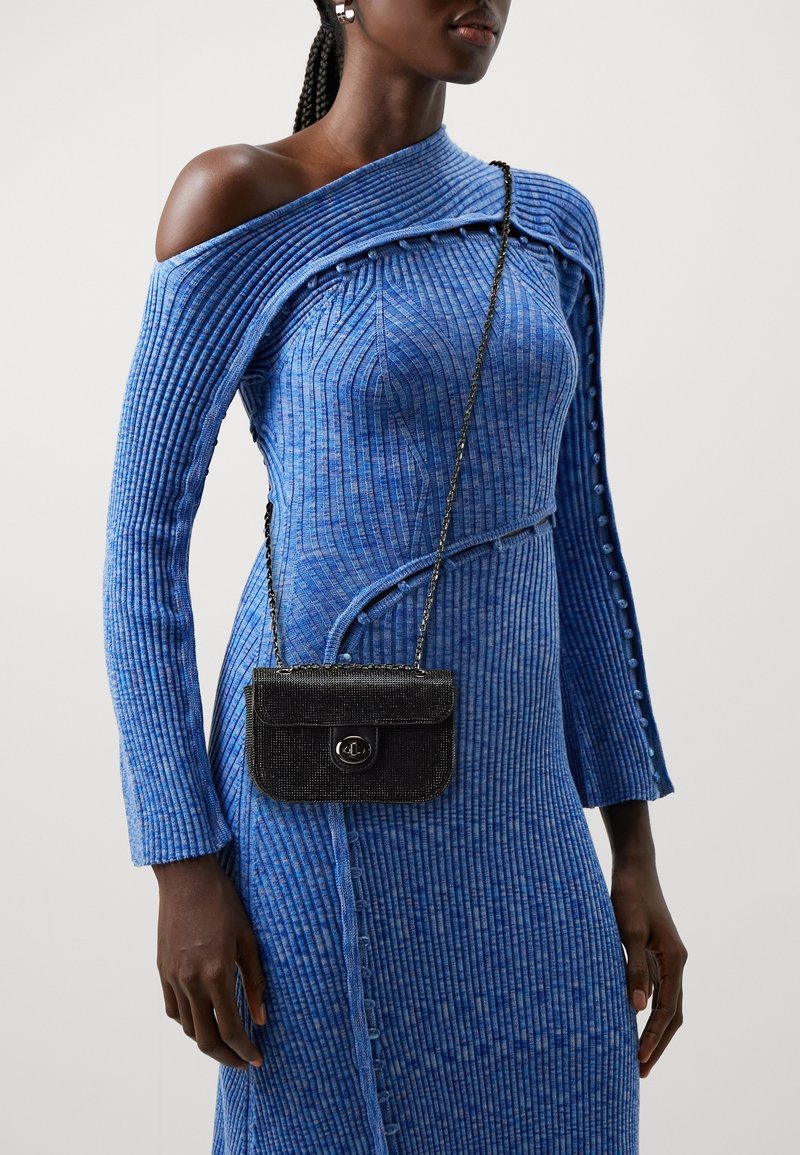 Abito a maglia blu a coste con design off-shoulder, caratterizzato da dettagli con bottoni; borsa nera testurizzata con catena e dettaglio logo.