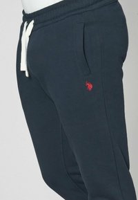 Pantaloni della tuta blu navy realizzati in cotone misto, con due tasche laterali, una vita elastica con cordino e un emblemma rosso sulla coscia.