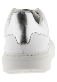 Baskets blanches avec un talon argent métallique, tige en cuir lisse, semelle en caoutchouc et détails de couture blancs, conçues pour un usage décontracté.