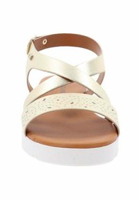 Sandali con cinturini incrociati in metallo dorato, tomaia perforata color crema, soletta marrone e suola piatta bianca. Dettaglio con chiusura a fibbia regolabile.
