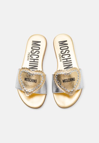 Silverfärgade slidesandaler med ett stort guldhjärta med nitar, guldaccenter och svart "Moschino Teen"-logotyp på en metallisk sula.