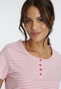 Pink and white striped short-sleeve shirt with a rounded neckline, featuring four pink buttons along the placket and smooth fabric texture.