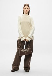 Μπεζ και εκρού πουλόβερ με φαρδιά μπάρα χρώματος και ριμπ ζώνη, συνδυασμένο με σκούρα καφέ παντελόνια με φαρδύ πόδι και καφέ δερμάτινη τσάντα με δομημένο σχήμα.