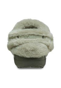 Parte trasera de un zapato Crocs, peludo y de color beige claro; textura gruesa y suave con una suela de goma verde; logotipo grabado en la correa.