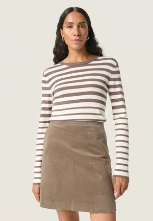 Gestreepte lange mouwen top in wit en bruin, gecombineerd met een bruine corduroy rok. De top heeft een ronde halslijn en aansluitende mouwen.