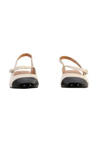 Bailarinas beige y negras con punta redonda, capa de charol negro y correa ajustable en el tobillo. Material de cuero suave.