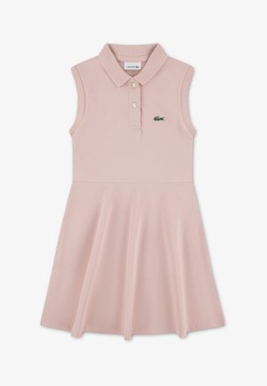 Vestido tipo polo en suave algodón rosa, diseño sin mangas, falda acampanada, con un pequeño logo verde de Lacoste en el pecho y tres botones en el cuello.