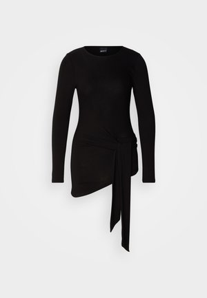 Top negru cu mâneci lungi, realizat dintr-un material moale și elastic; are un detaliu cu nod lateral și o tiv asimetric.