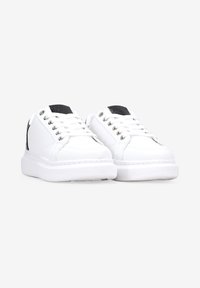 Sneakers bianchi in materiale sintetico liscio, punta rotonda, suola piatta e accenti neri testurizzati sul tallone. Sei occhielli argentati per i lacci.
