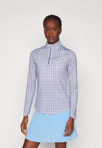 Langermet topp i lyseblå med kvart glidelås. Har et geometrisk mønster i rosa, lilla og hvit, laget av et glatt, elastisk stoff.