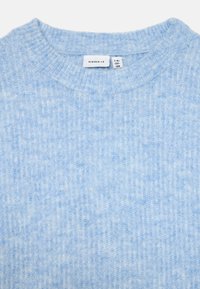 Lyseblå strikket genser med ribbestruktur, med rund hals og et merke som sier "name.it." Stoffet ser mykt og koselig ut.