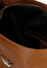 Brązowa skórzana torebka na zamek błyskawiczny. Wnętrze wyłożone jest czarnym materiałem, a na zewnętrznej stronie znajduje się akcent z logotypem.