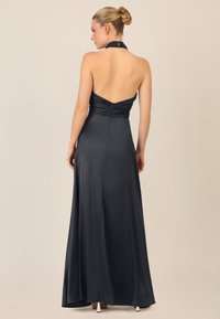 Abito da sera in satin nero con scollatura a halter, corpetto aderente e gonna fluida. Presenta arricciature sul retro e una zip nascosta.