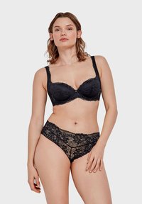 Soutien-gorge en dentelle noire avec armatures, arborant des motifs floraux, des bretelles réglables et un nœud décoratif à l'avant ; assorti à des culottes en dentelle.