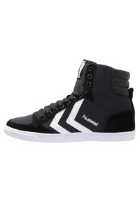 High-top sneakers with a black canvas upper, suede accents, white rubber sole, and bold white chevron logo. Features metal eyelets and padded collar.