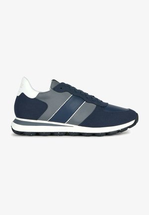 Sneaker sportive blu navy con accenti grigi, materiali lisci e testurizzati, suola bianca piatta e due dettagli a strisce diagonali.