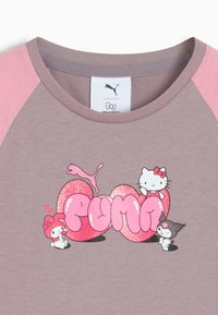 Fioletowa i różowa koszula z różowym, błyszczącym napisem "PUMA", z Hello Kitty i dwoma postaciami z Sanrio wokół logo.