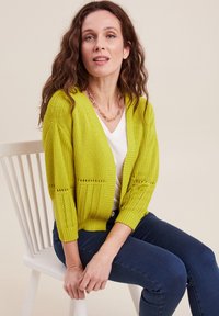 Cardigan lavorato a maglia verde lime con vestibilità ampia, apertura frontale e maniche a tre quarti, caratterizzato da un motivo in pizzo lungo l'orlo e le maniche.