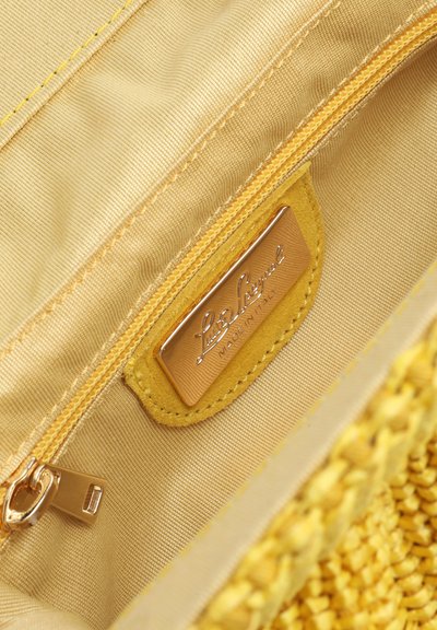 Intérieur d'un sac à main en tissu jaune avec une poche zippée et une étiquette en cuir cousue portant l'inscription « Fabriqué en Italie ».