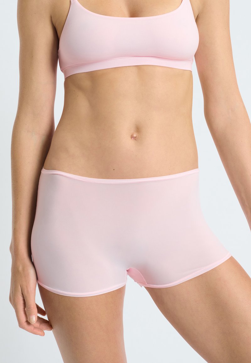 Pantaloni corti hipster rosa chiaro realizzati in un tessuto liscio e elasticizzato, con una vita senza cuciture e una copertura minima delle gambe, progettati per il massimo comfort.