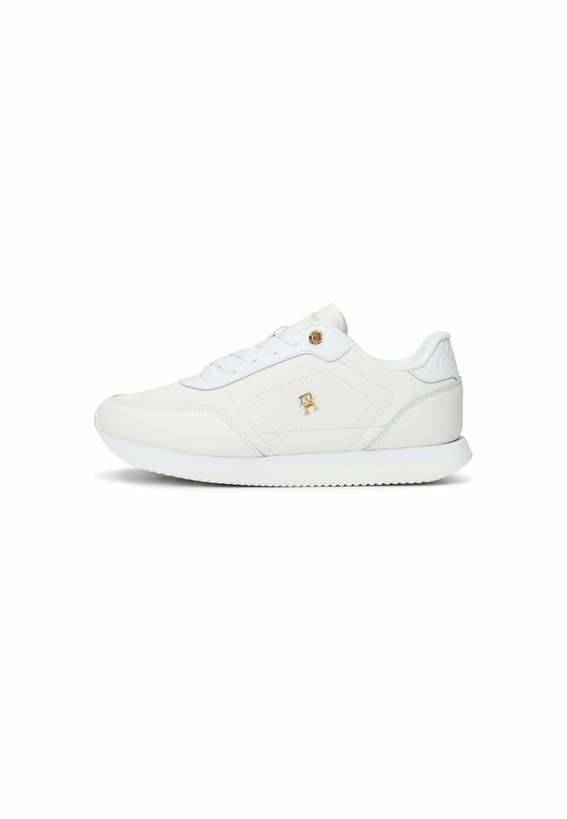 Zapatillas sintéticas blancas con una textura suave, que presentan un collar y lengua acolchados, punta redonda y detalle de emblema dorado. Suela de goma.