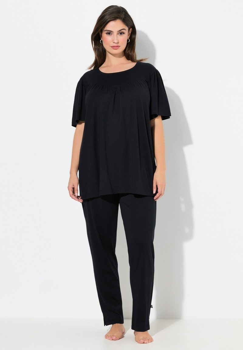 Ensemble de loungewear noir comprenant un haut ample avec des manches courtes bouffantes et un pantalon avec des fentes aux chevilles, fabriqué en tissu doux et léger.