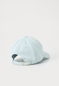 Light blue denim cap with a curved brim, adjustable strap, and stitched detailing. The back features ventilation holes.