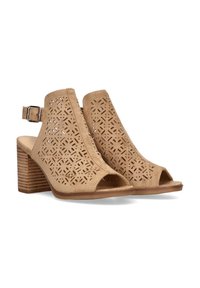 Sandalias de tacón abiertas de dedo en color bronce, con parte superior de ante perforado, tira ajustable en el tobillo y tacón de madera apilada con rayas horizontales.