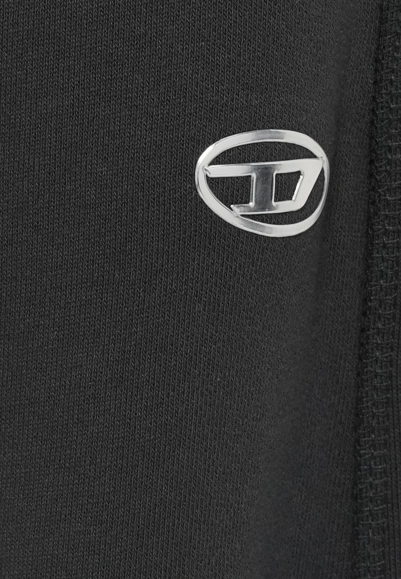 Tela negra con textura suave, con un logo plateado en el lateral. Diseño sencillo sin patrones ni acentos adicionales.