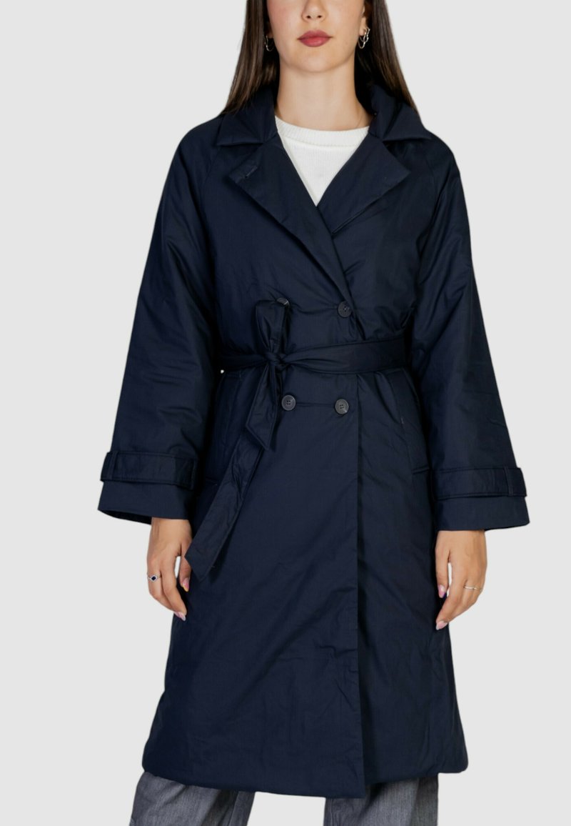 Trench coat blu navy con vita a cintura, bottoni doppi, colletto ampio e polsini grandi. Tessuto liscio e design fino al ginocchio.