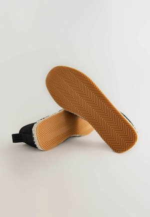 Fekete szövött slip-on cipők, halszálka mintás gumitalppal és kontrasztos fehér texturált szegéllyel.