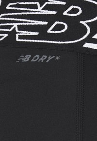 Czarna sportowa tkanina o teksturowanym prążkowaniu, z dużym białym logo "B" i małą szarą metką "BDRY". Gładka, elastyczna powierzchnia.