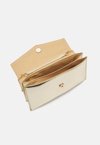 Gold metallic wallet with a smooth finish, button closure, and beige interior. Features multiple compartments and a zippered section.