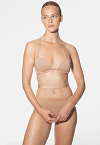 Naadloze huidkleurige bh met dunne bandjes en bijpassende hoge taille slipjes. Gladde textuur en minimalistisch ontwerp, met geen zichtbare hardware.