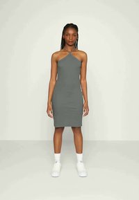 Vestido cinza de alças com um design justo, até aos joelhos, feito de um tecido suave. Usado com ténis brancos e meias altas.