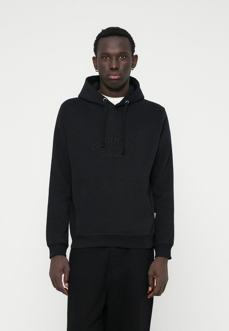 Sweatshirt à capuche noire en tissu doux, avec une poche avant et un logo brodé "ORIGINALS" ton sur ton. Coupe classique avec des poignets côtelés.
