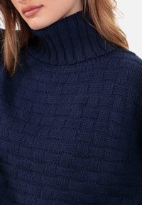 Pull col roulé bleu marine à motif tissé texturé, doté d'un col haut et de finitions côtelées, confectionné en matière tricotée douce.