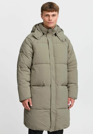 Long, padded coat in light olive green, featuring a hood, front zipper, and two side pockets with a quilted design and streamlined silhouette.