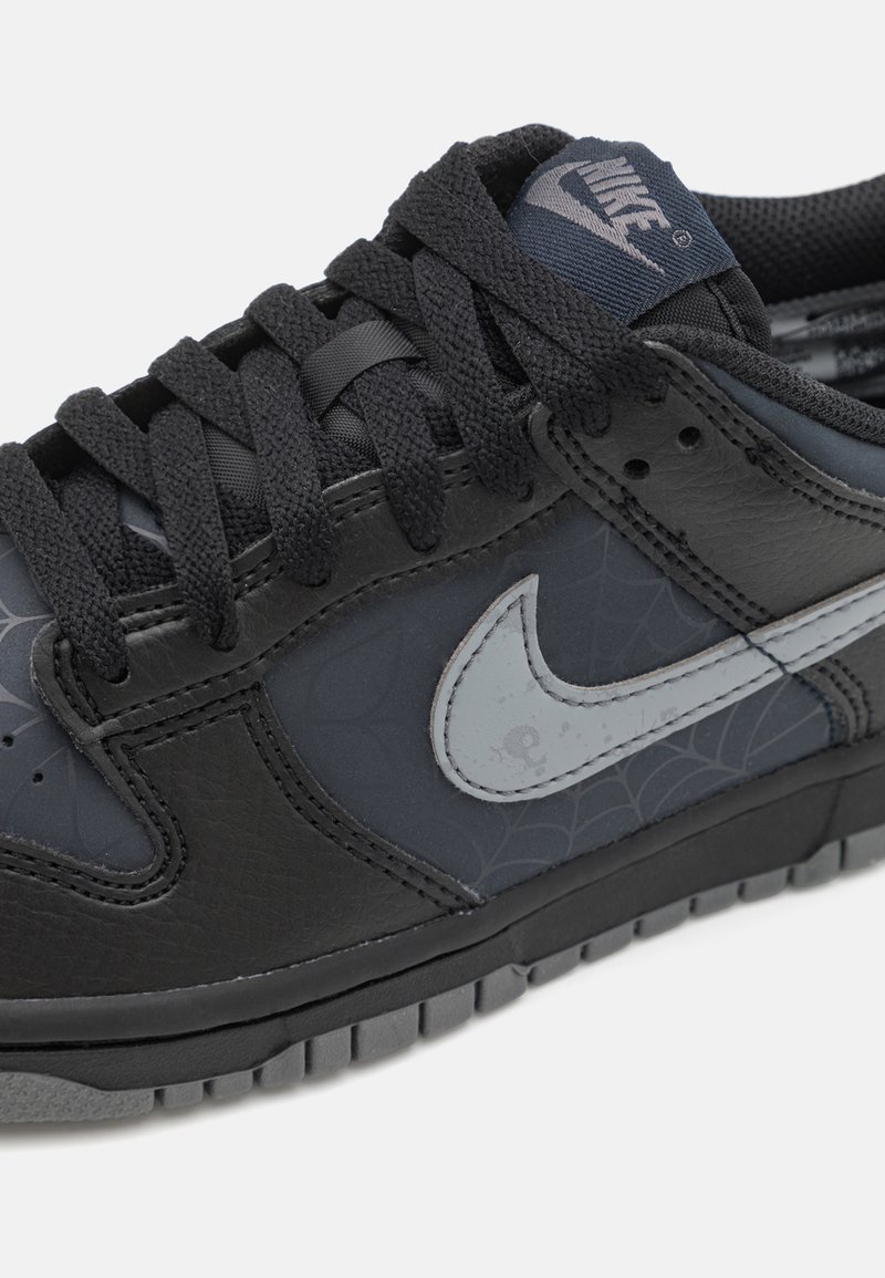 Czarne sneakersy wykonane ze skóry i tkaniny, z motywem pajęczyny, szarymi akcentami i wyraźnym logo Nike w kształcie łyżwy.