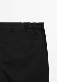 Black pants with an elastic waistband and a single back pocket. The fabric is smooth with a matte finish and a simple, minimal design.