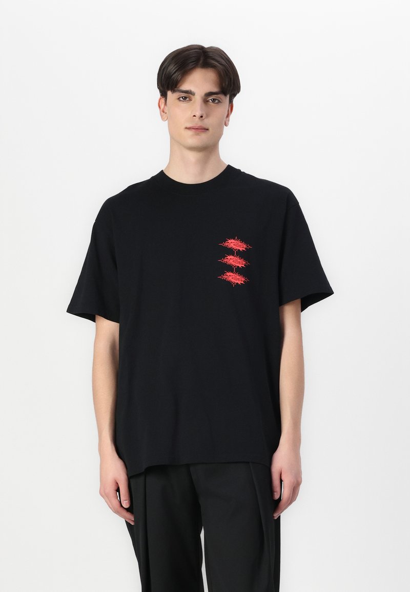 Zwart katoenen T-shirt met korte mouwen, voorzien van vier rode grafische ontwerpen op de linkerkant van de borst. Ontspannen pasvorm met een ronde halslijn.