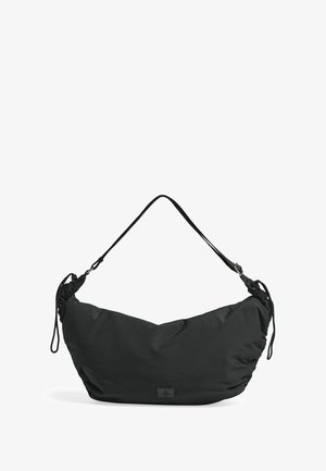 Melna pleca soma no mīksta auduma ar noapaļotu formu, regulējamu siksnu un smalku zīmola detaļu. Vienmērīga tekstūra visā somā.