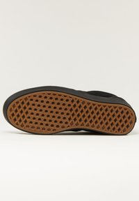 Černá podrážka tenisky s texturovaným gumovým povrchem a hexagonálními vzory. Okraj je hladký a přechází do plochého designu.