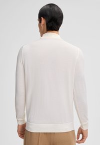 Witte lange mouwen gebreide pullover met een subtiele textuur, omslagmanchetten en een ribbelige zoom. Heeft een zachte kraag en een gladde stof.