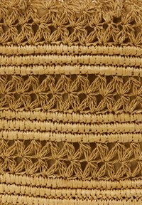 Geweven natuurlijk rieten tas met een textuur oppervlak met een bloemmotief. Het ontwerp bevat afwisselend ondoorzichtige en open geweven secties.
