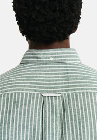 Camicia a righe verdi e bianche realizzata in un tessuto leggero, con colletto button-down e piega sul retro per un tocco in più.