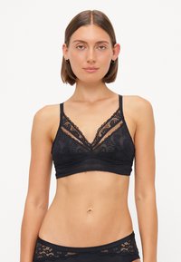 Black lace bralette with a V-neck design, scalloped edges, and adjustable straps. Features intricate floral patterns and a soft texture.