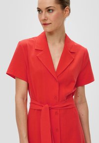 Rotes, kurzärmliges Kleid aus strukturiertem Stoff, mit eingekerbtem Kragen und Knöpfen vorne. Verfügt über einen gebundenen Taillengürtel für eine figurbetonte Silhouette.