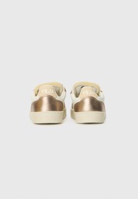 Hvite sneakers med metallisk roségull aksenter, glatt lærtekstur og beige gummisåler. "VEJA"-logoen er sydd på hælen.