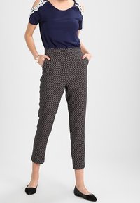 Top azul marino con hombros descubiertos y detalles de encaje, combinado con pantalones ajustados de patrón con un diseño geométrico en colores oscuros. Bailarinas negras.